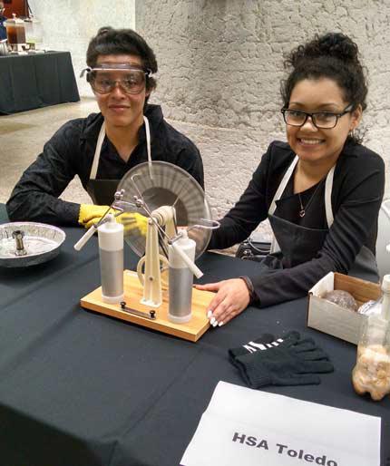 Two students sitting at a desk with a science experiment at science fair