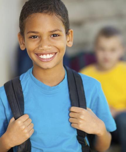African Ameriacan 12 year old boy with his backpack, smiling at camera